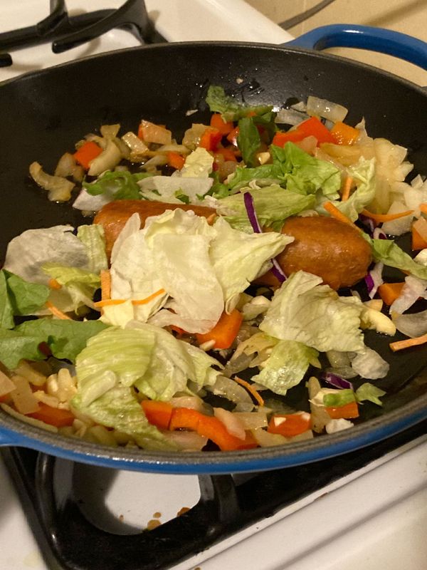 Beyond Meat sausage and veggies cooking in a Le Creuset skillet